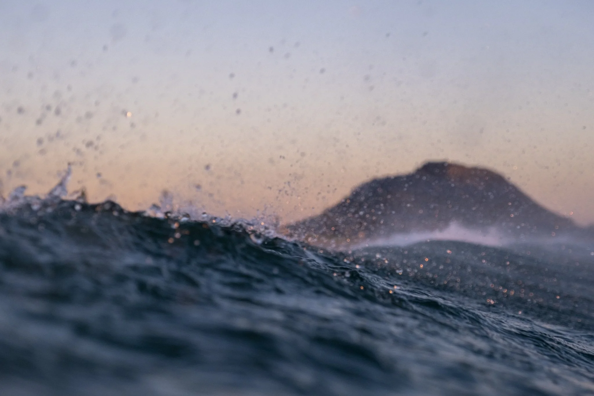 Water-level ocean view of Mauao Mount Maunganui at dusk, photographed by Lou Burton.