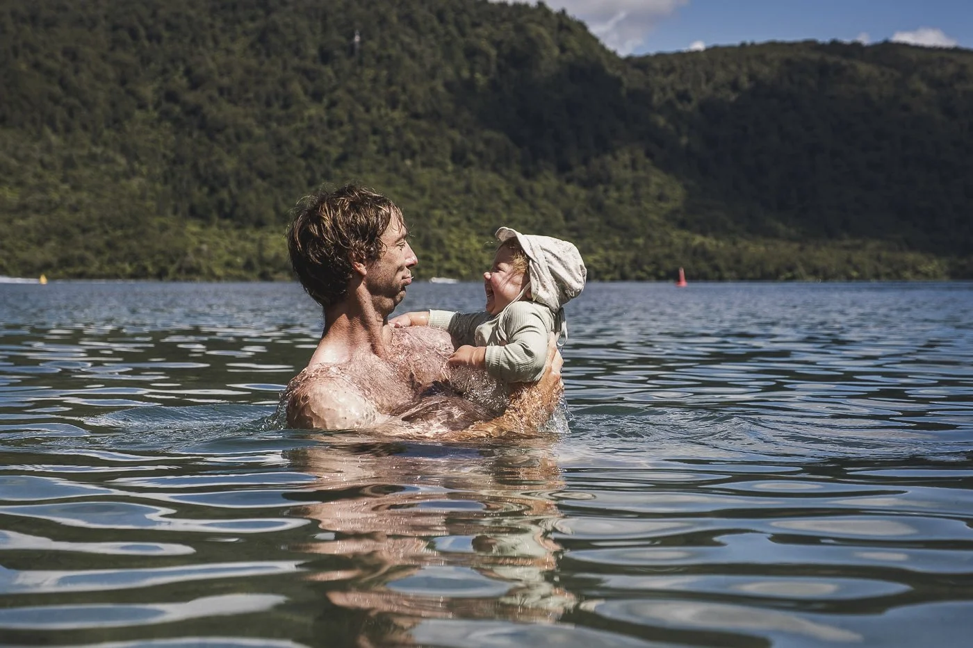 Dad swimming with his toddler at Lake Tikitapu Blue Lake in Rotorua, New Zealand