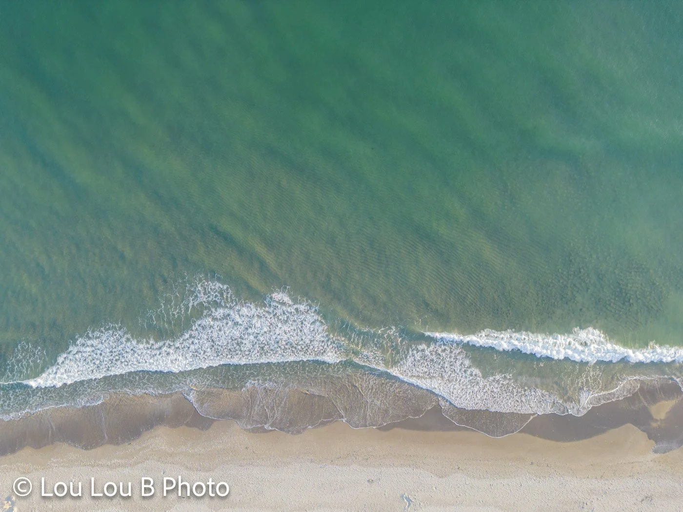 Aerial view of waves meeting the sandy coastline at Mount Maunganui
