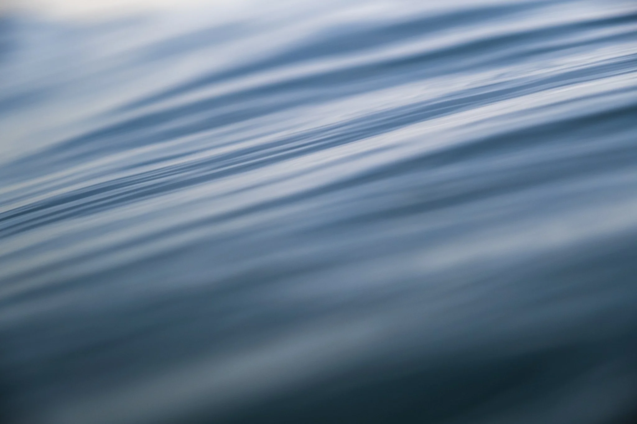 Abstract blue ocean surface with soft ripples and reflected light.