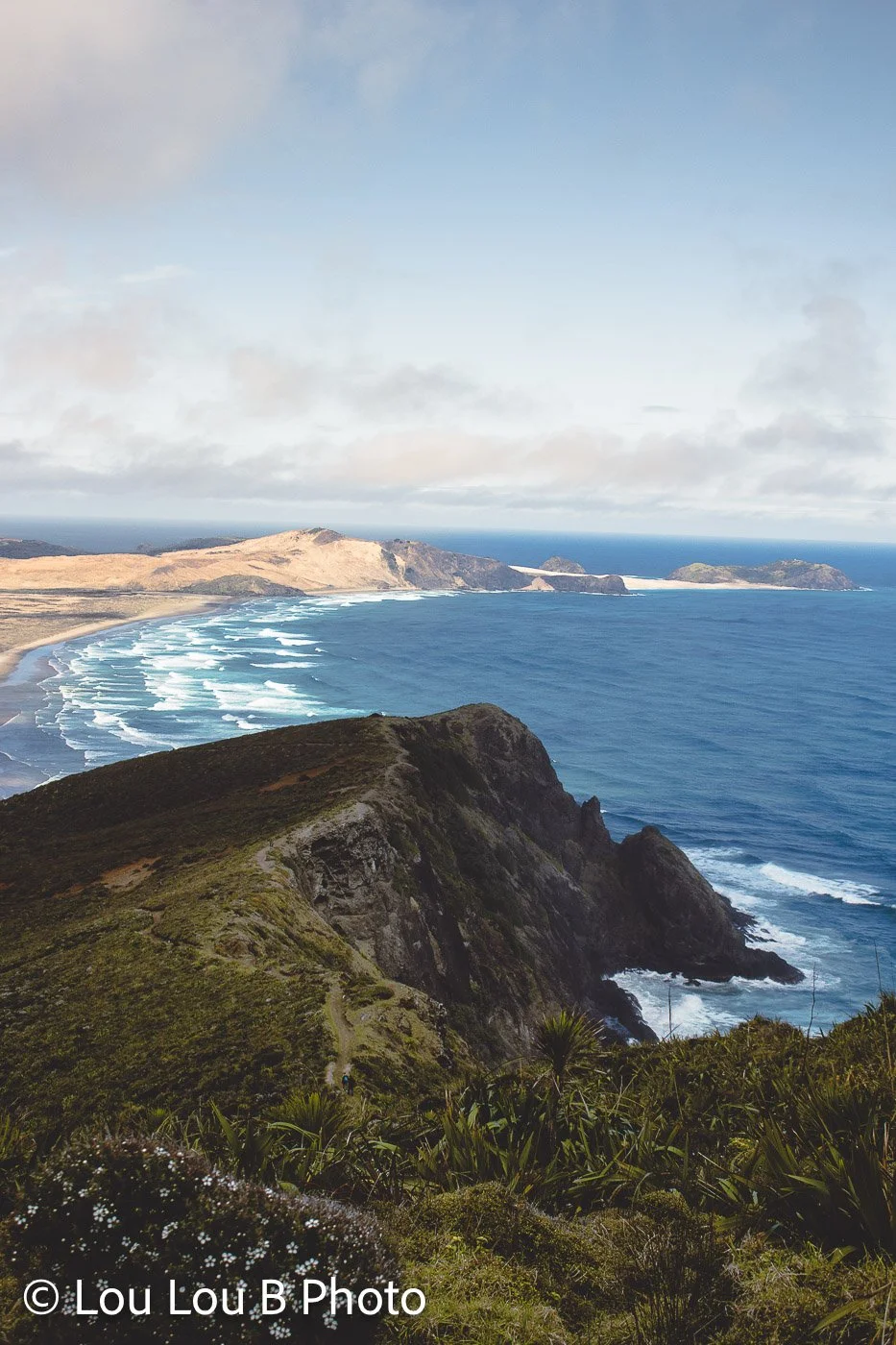 Elevated view across a rugged coastal headland and vivid blue ocean coastline.