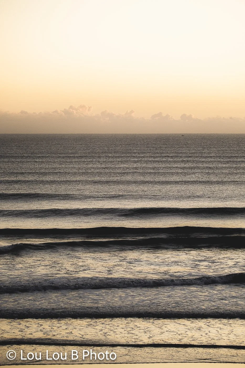 Minimal ocean horizon with parallel waves beneath a hazy golden sky.