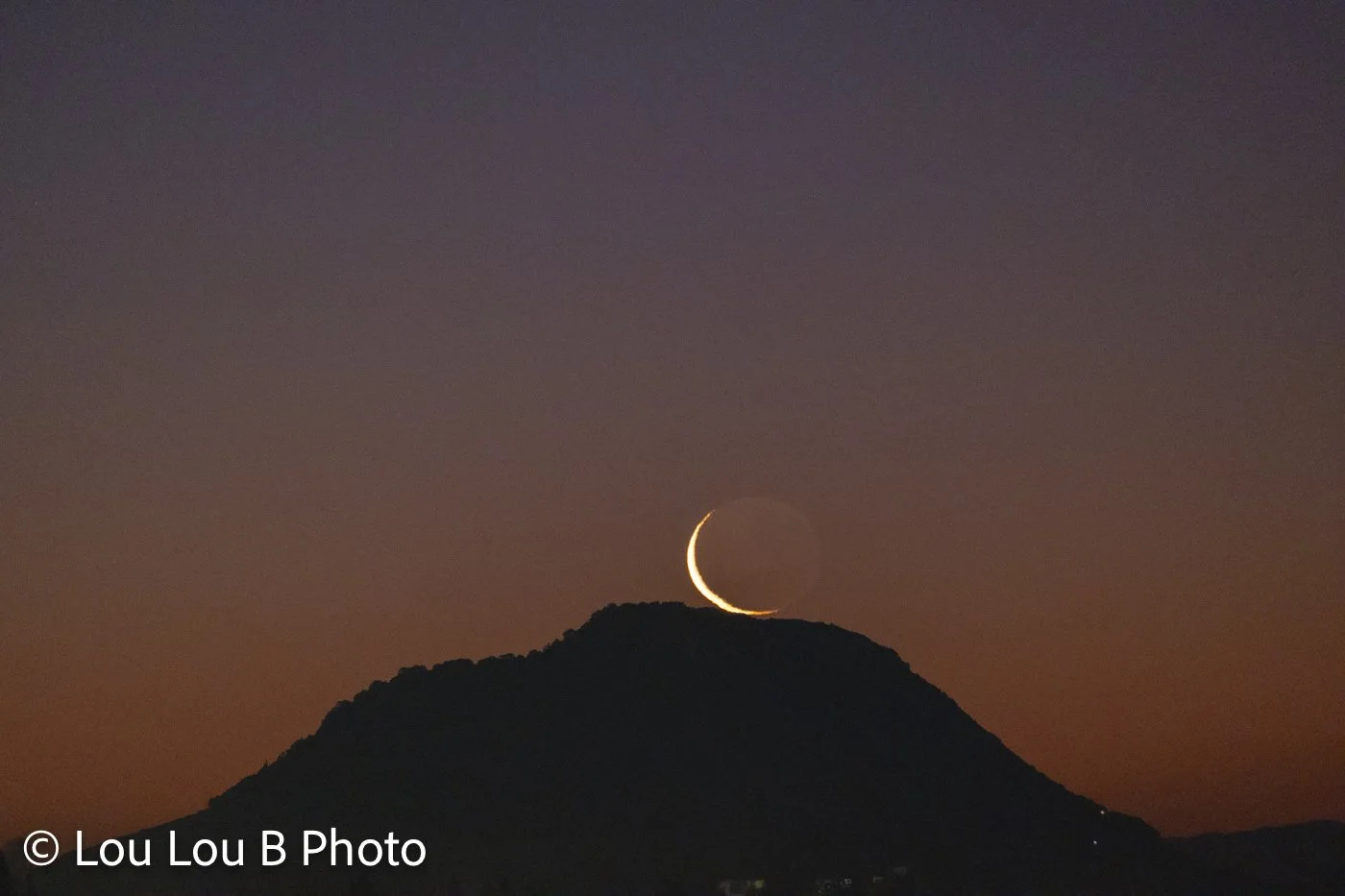 Crescent moon setting behind Mauao at Mount Maunganui at twilight