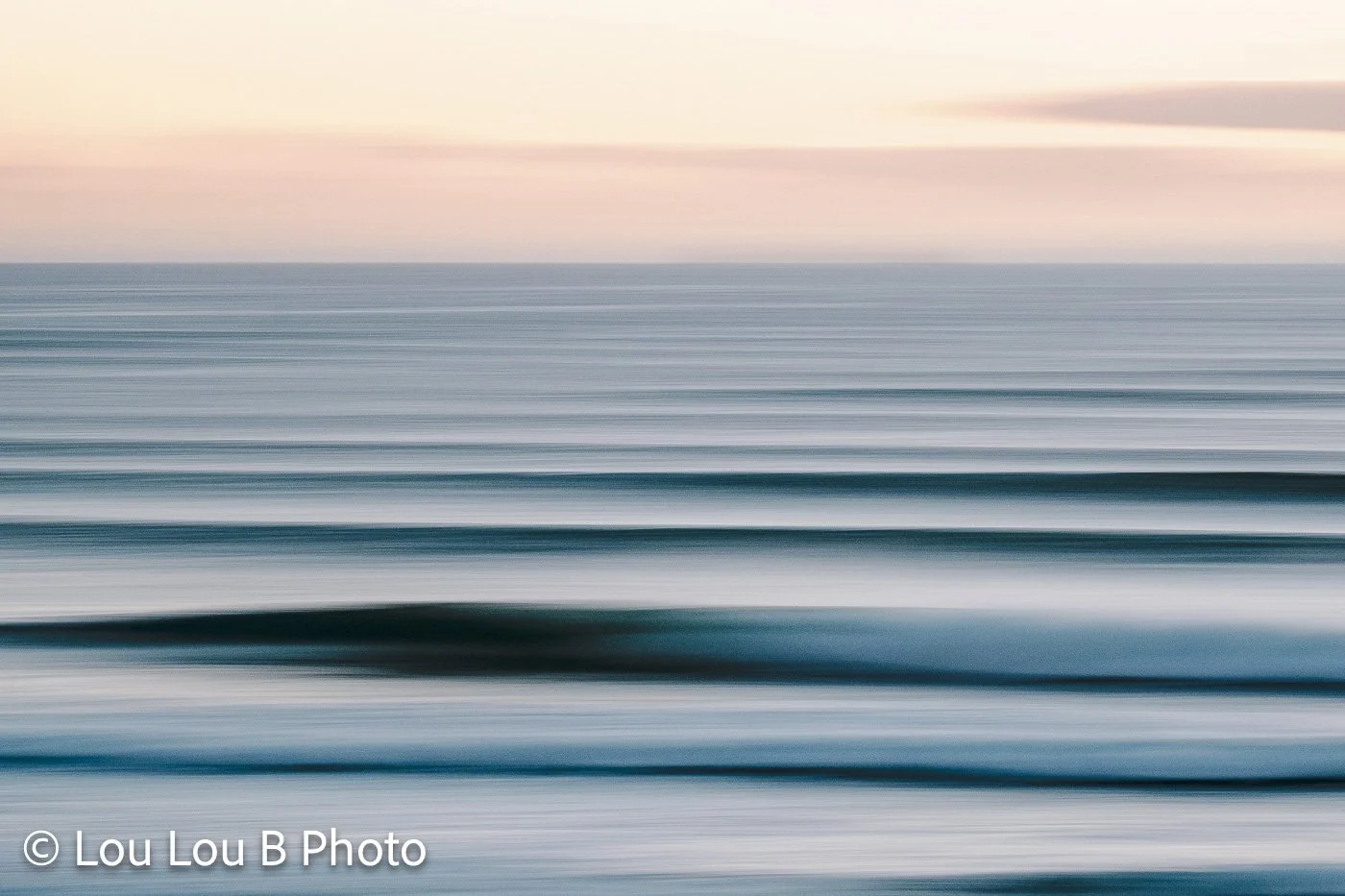 Abstract long-exposure seascape with bands of turquoise, blue and soft pink.
