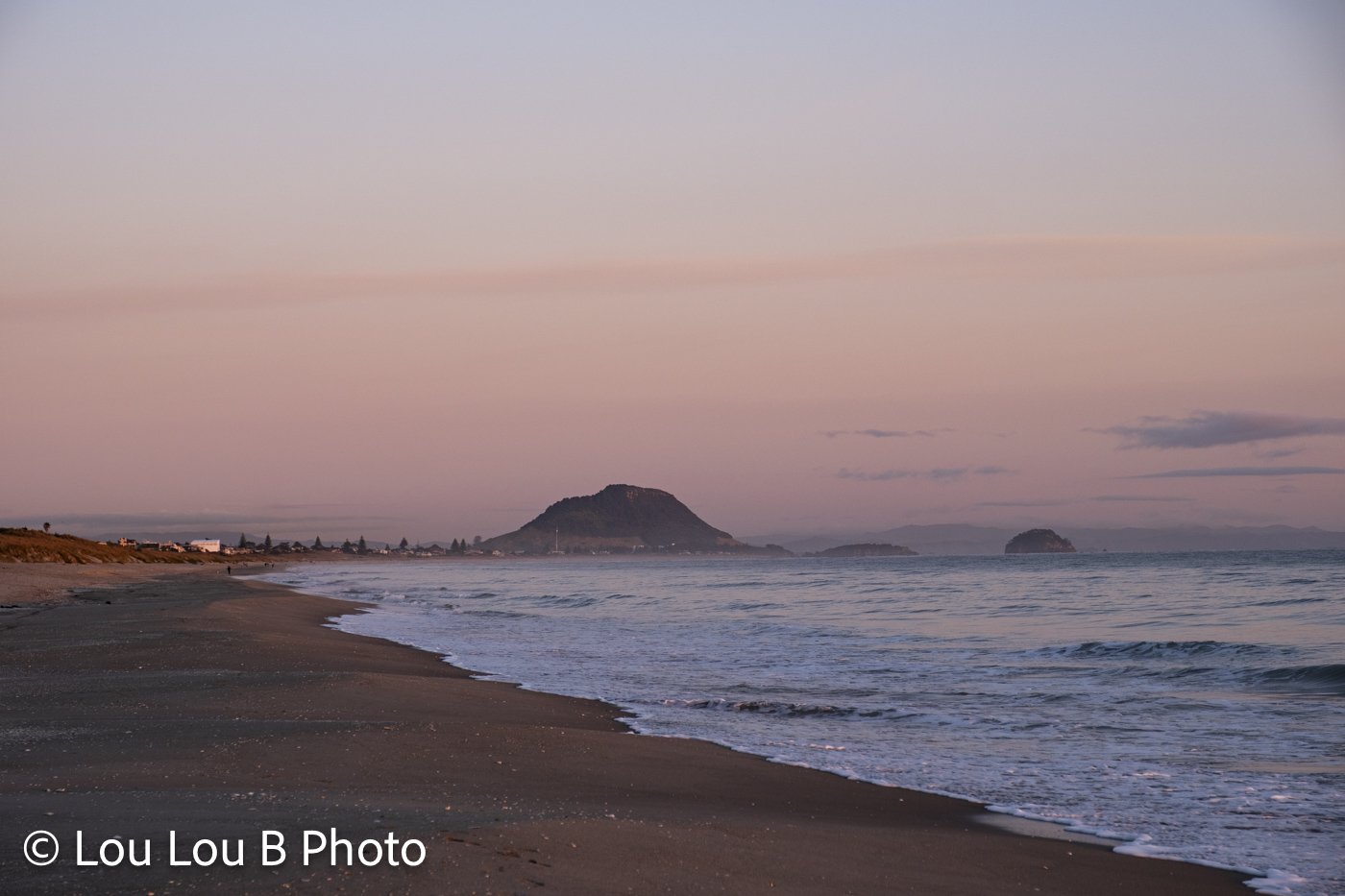 Mauao viewed along Mount Maunganui beach beneath a pink and blue twilight sky