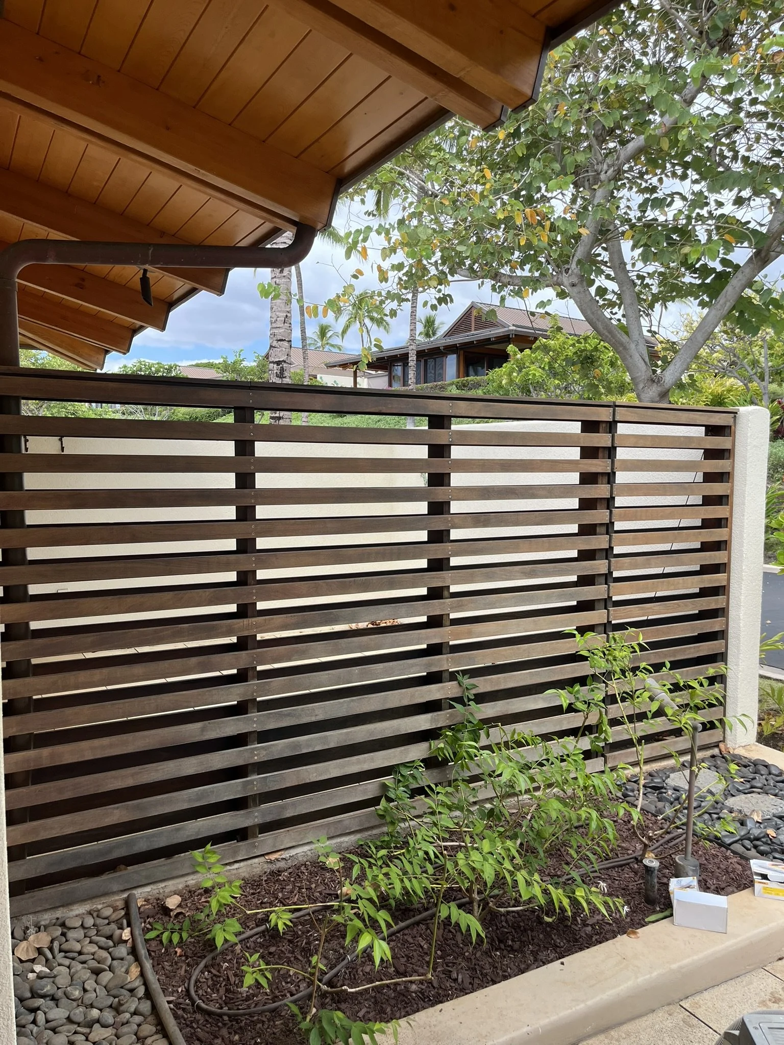 Backyard and exterior painting project at a Maui home - porch view of a wood fence and garden, by Maui Home Refinishing.