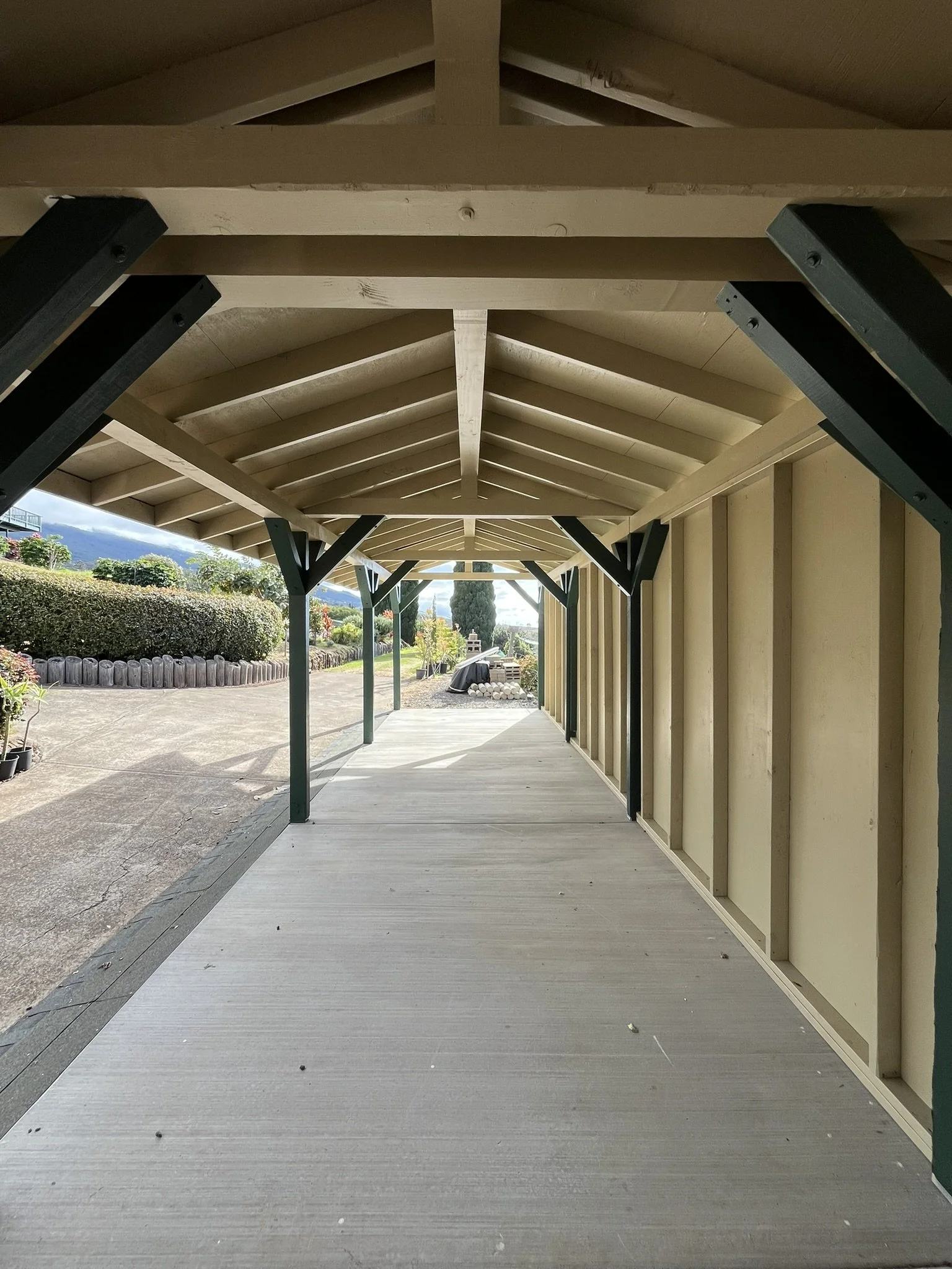 Exterior painting project at a Maui home - covered wooden porch with support beams and walkway, by Maui Home Refinishing.
