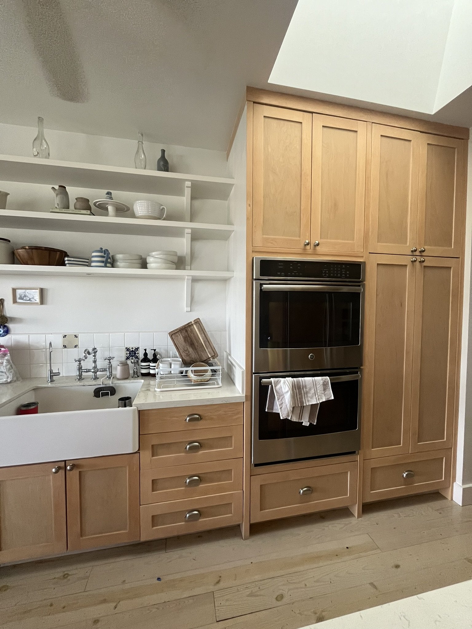 Cabinet refinishing in a Maui home kitchen - light wood cabinets, open shelving, farmhouse sink, and stainless steel oven, by Maui Home Refinishing.