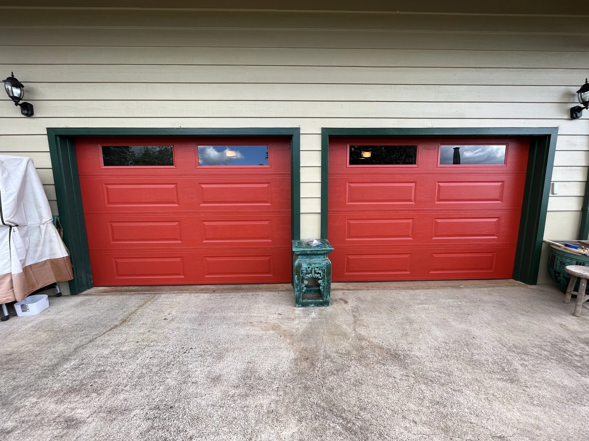 Exterior house painting in Maui - red garage doors with green trim on a beige siding home, by Maui Home Refinishing.