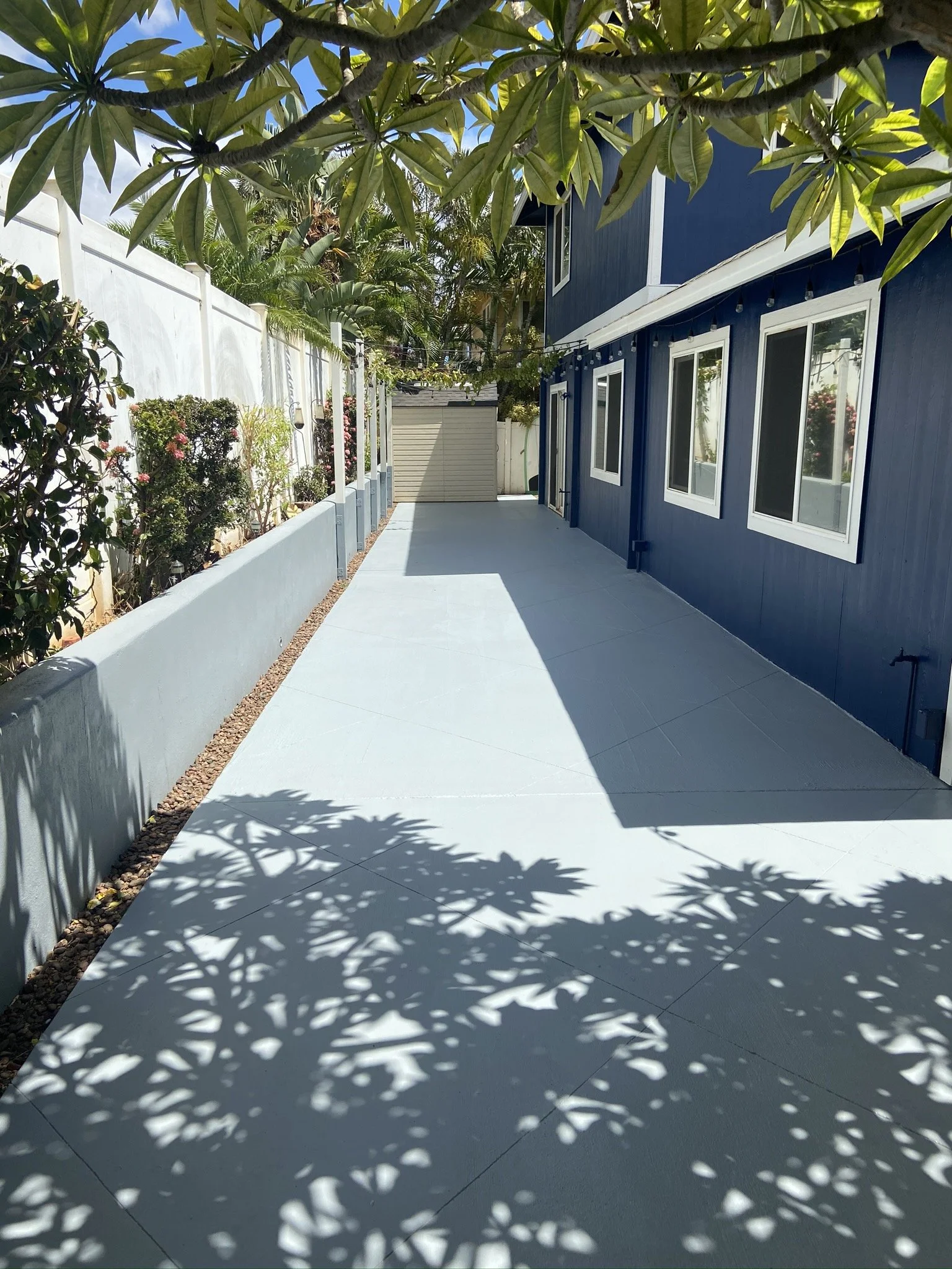 Exterior house painting project at a Maui home - backyard patio with a blue house and white-trimmed windows, by Maui Home Refinishing.