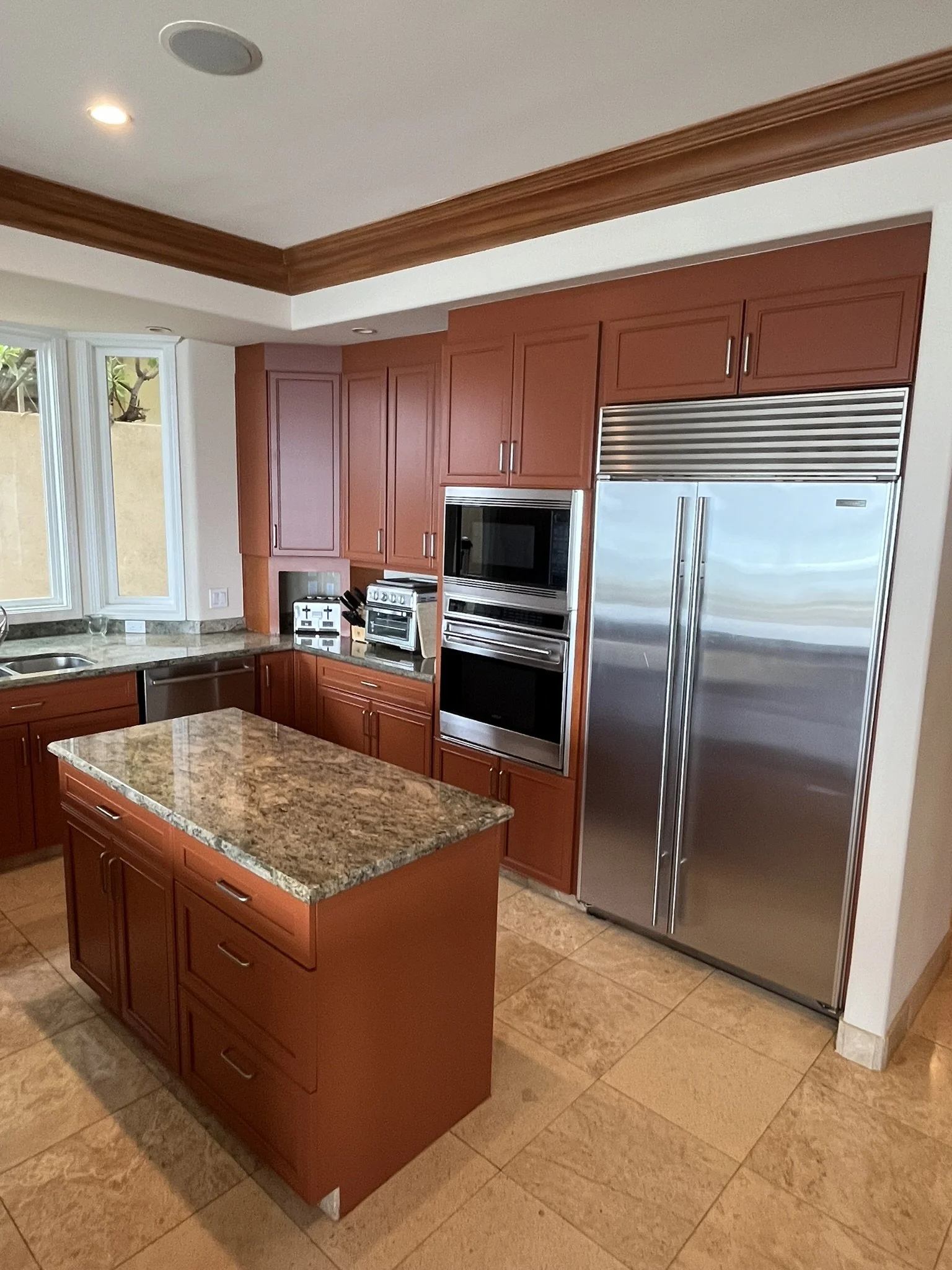 Cabinet refinishing in a Maui home kitchen - wood cabinets with granite island and stainless steel refrigerator, by Maui Home Refinishing.