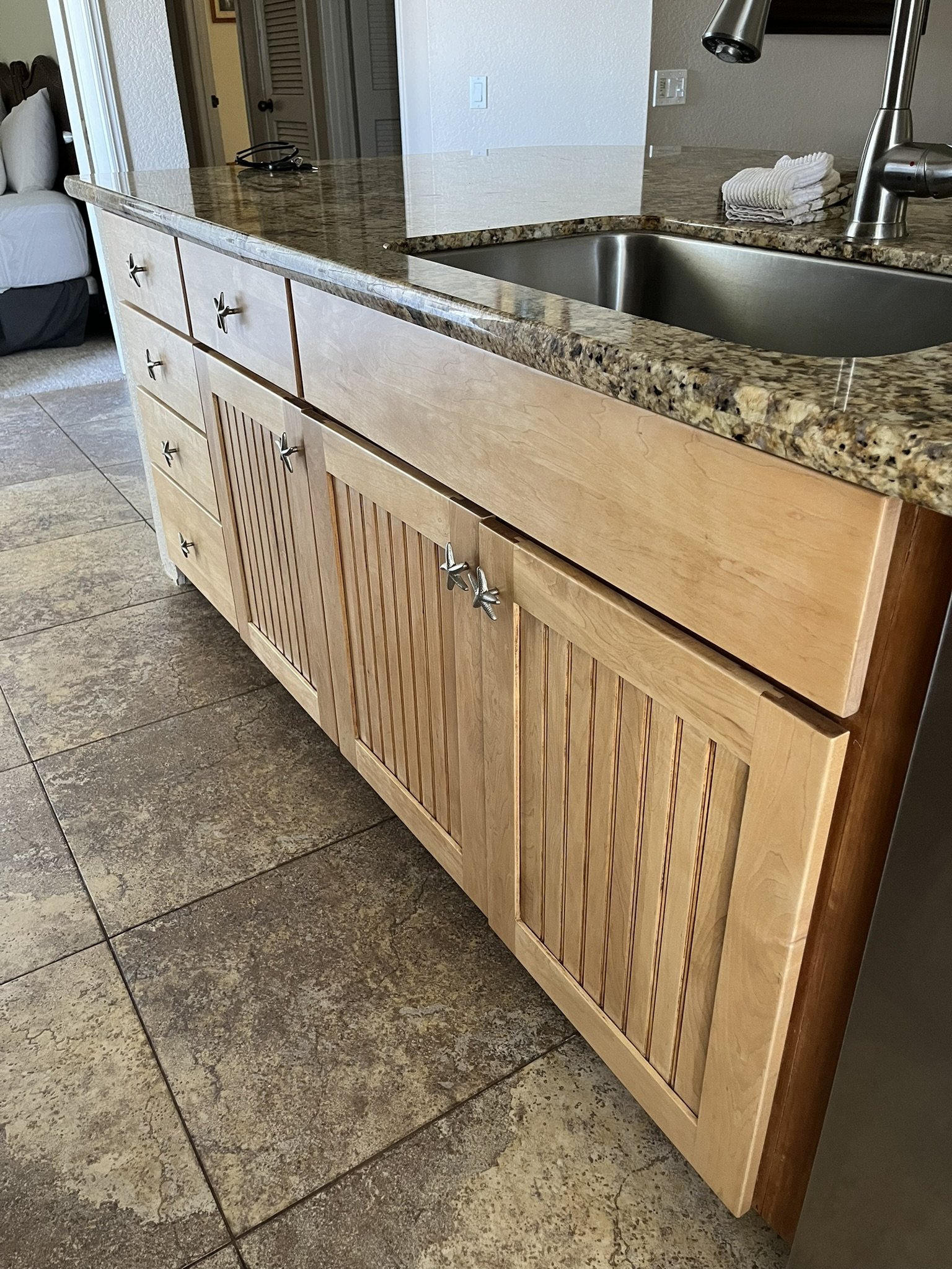 Cabinet refinishing in a Maui home kitchen - wood island with slatted cabinet doors and granite countertop sink, by Maui Home Refinishing.