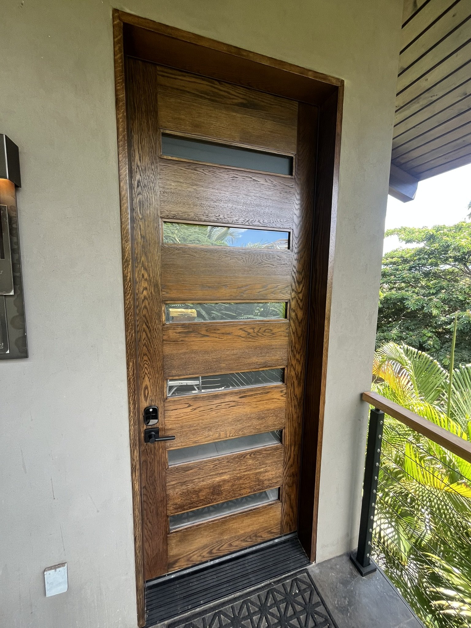 Hardwood door refinishing in a Maui home - exterior wood door with glass panels, part of a covered porch, by Maui Home Refinishing.