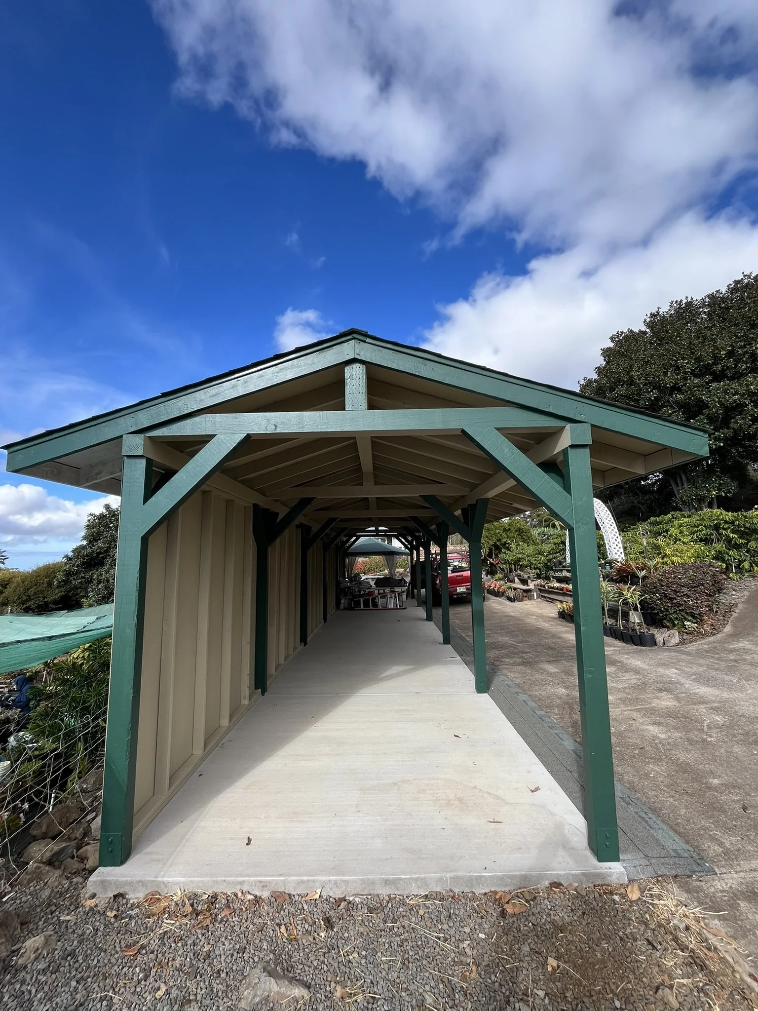 Exterior house painting in Maui - green covered walkway with wood support beams, by Maui Home Refinishing.
