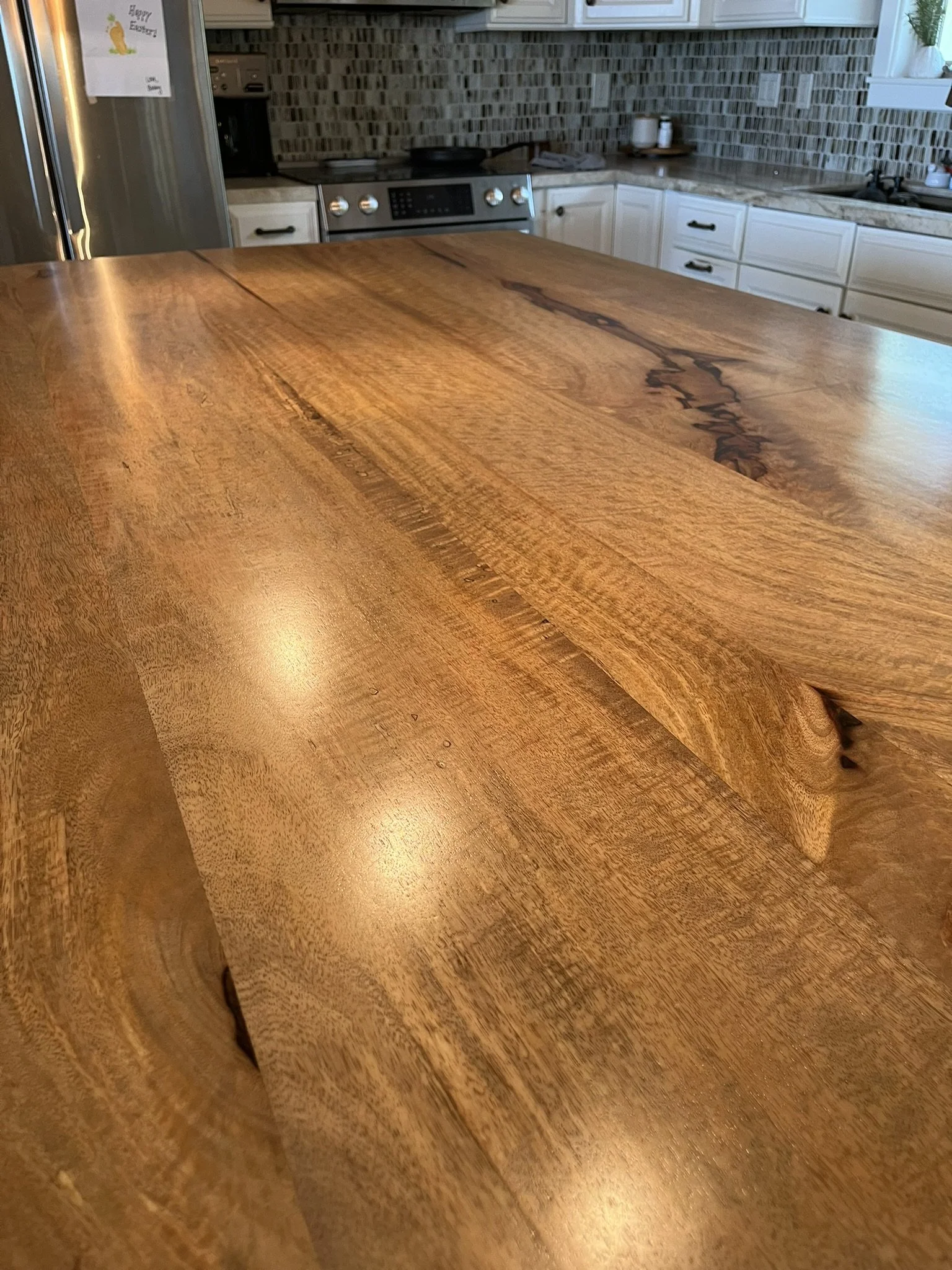 Hardwood refinishing close-up on a Maui home kitchen island - natural wood grain finish, with cabinets and appliances in the background.