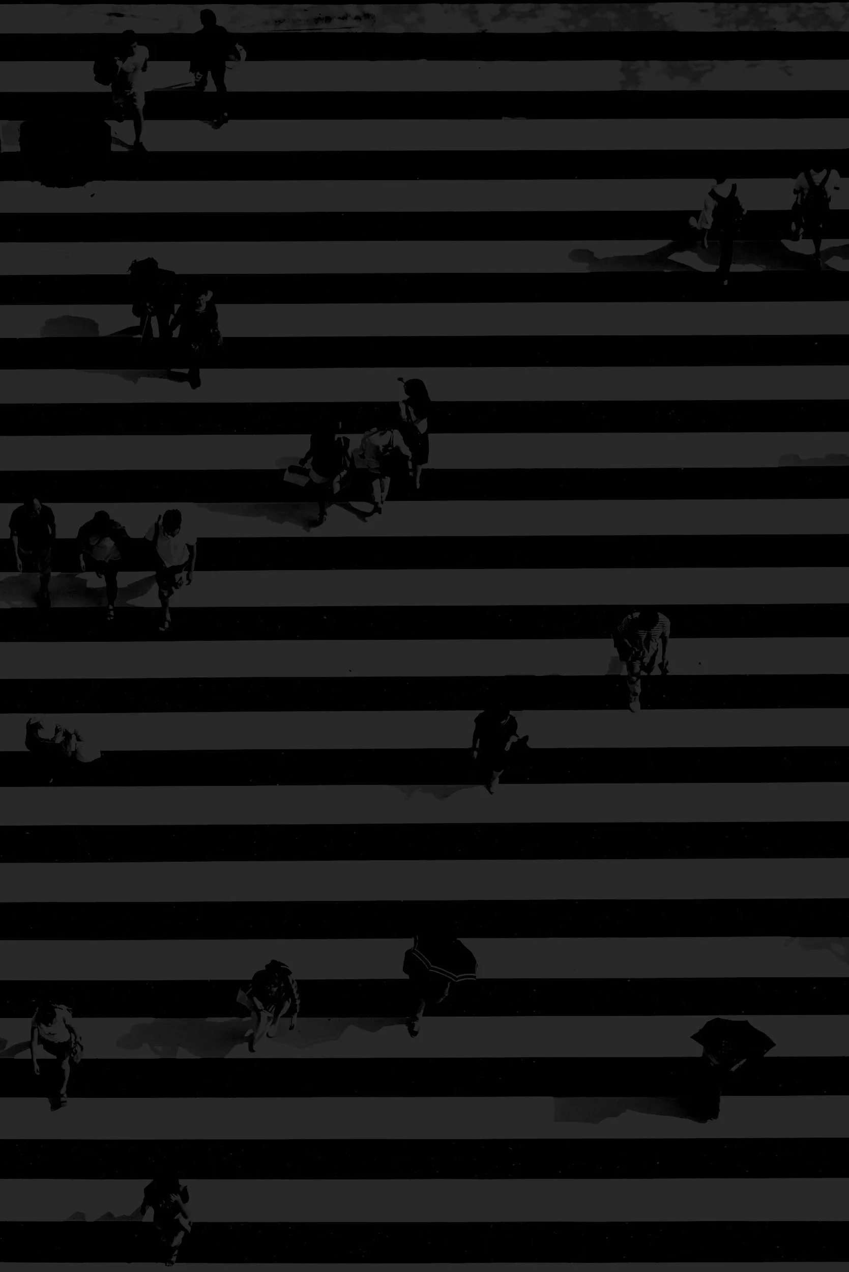 People crossing a street at a zebra crosswalk, some with umbrellas, under a dark sky.