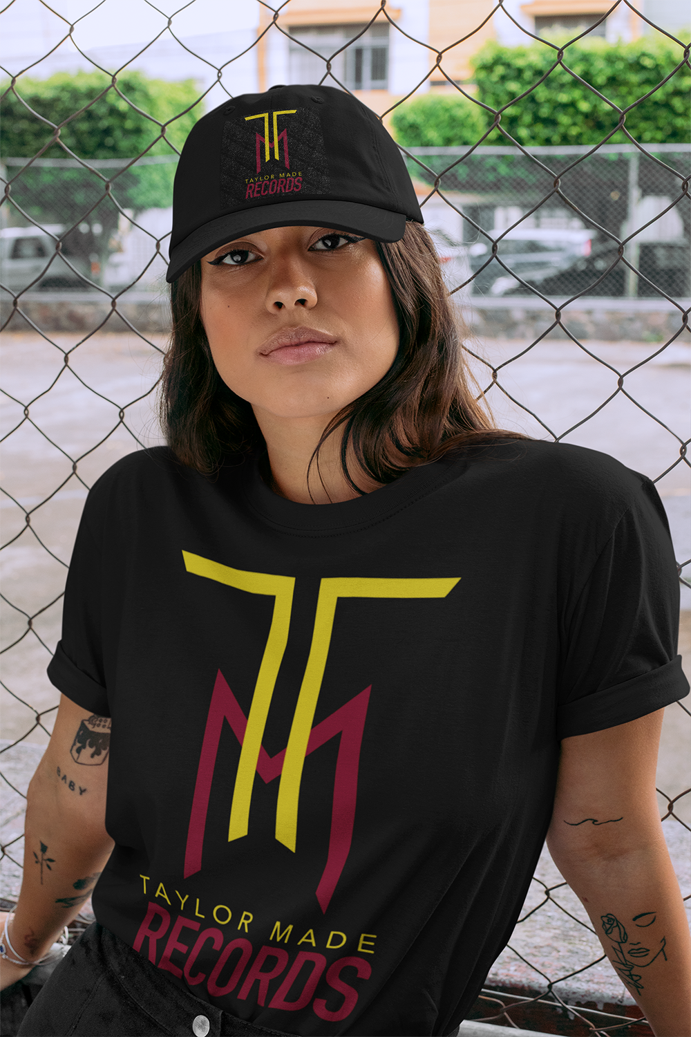 t-shirt-mockup-featuring-a-woman-wearing-a-dad-hat-by-a-chain-link-fence-28600.png