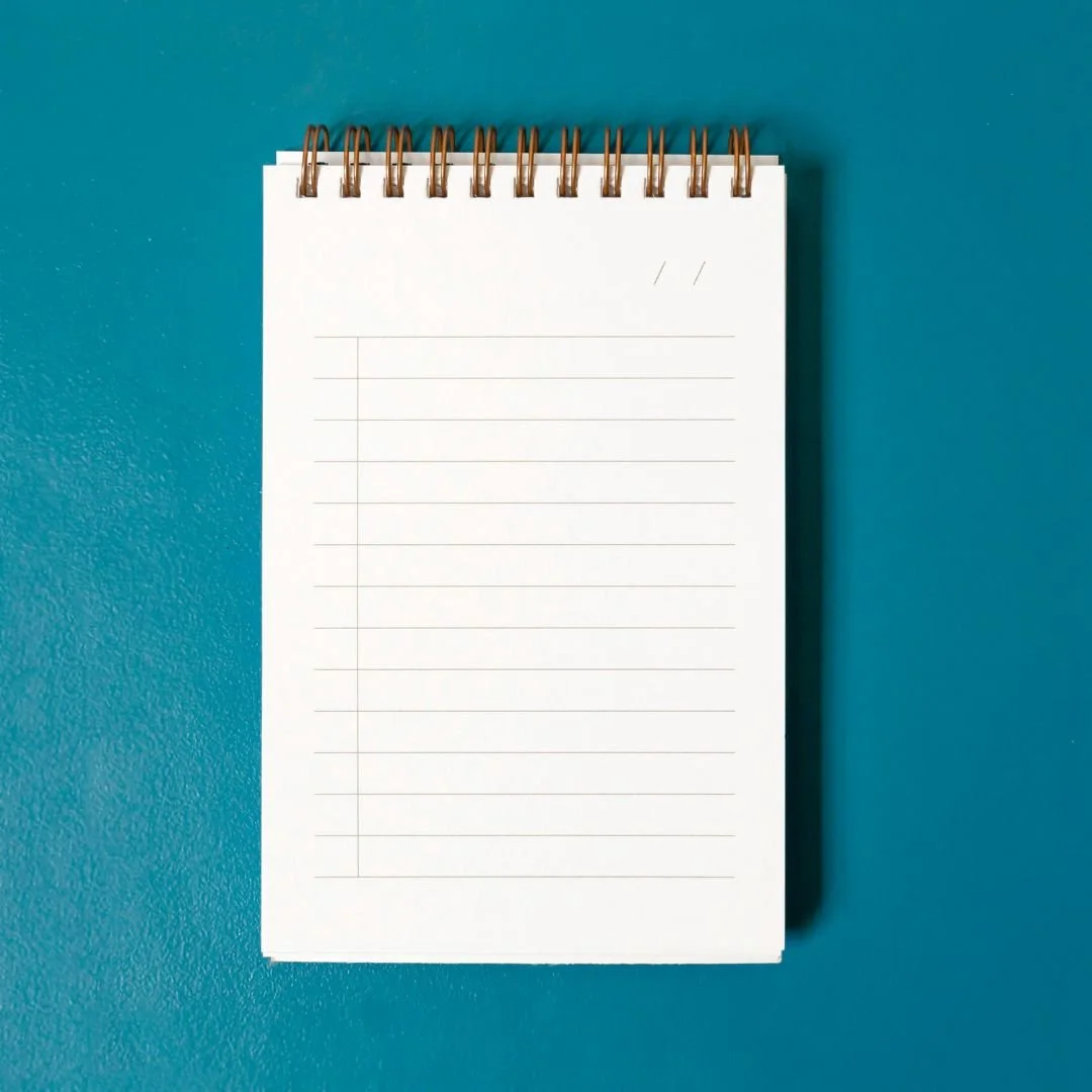 Spiral notepad on turquoise background, representing a nonfiction author getting tips from a book coach for traditional publishing contract