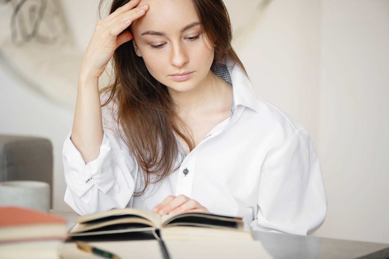 A nonfiction author studying an open book on her desk while preparing for the self publishing process