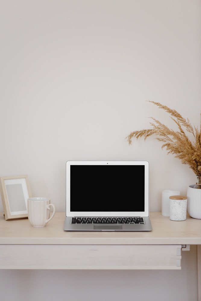 Open macbook on light wood desk, in an article about working with a self-publishing coach online