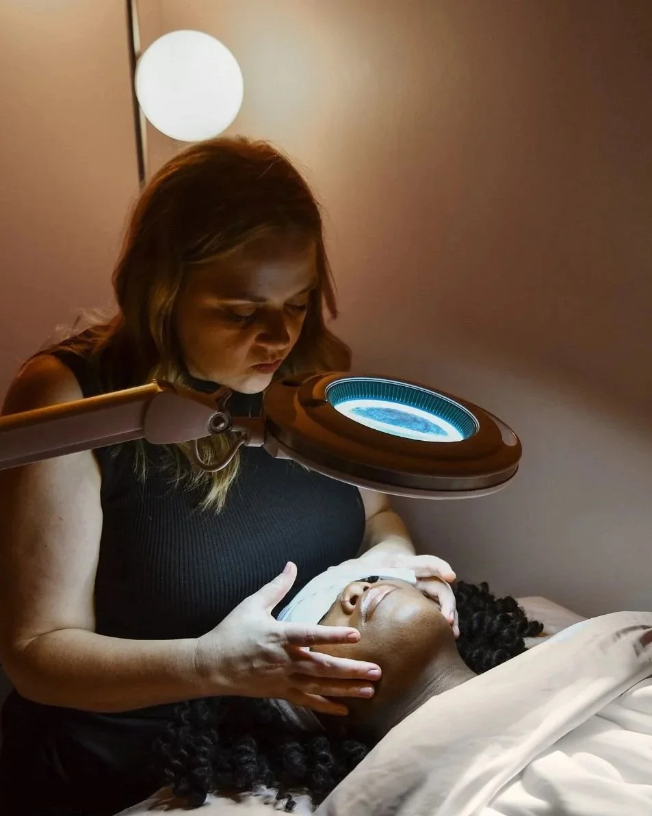 Heather Roberts, a licensed esthetician, gently placing her hands on a client’s face during a facial treatment.