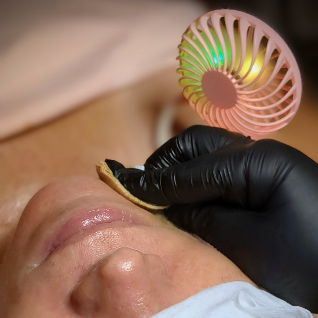 Heather Roberts, licensed esthetician, applying a chemical peel to a client's face