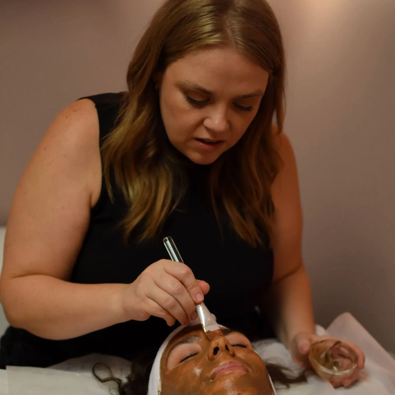 Close-up of Heather Roberts applying a soothing face mask treatment, showcasing a relaxing spa experience.