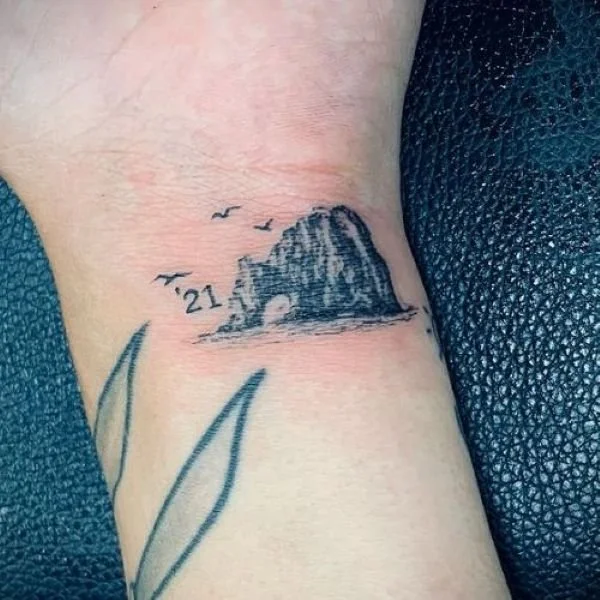 Wrist tattoo of Cabo Arch with frigate birds