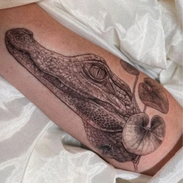 Tattoo of caiman head around lily pads