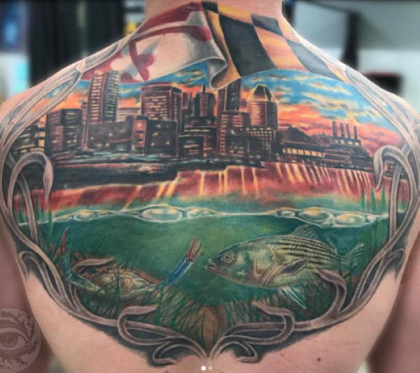 Tattoo of feeding rockfish under Baltimore skyline back