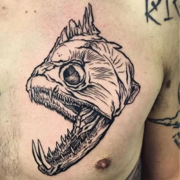 Black and white tattoo of payara skull on man's chest