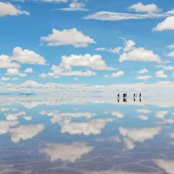 People standing on reflective Uyuni Salt Flats