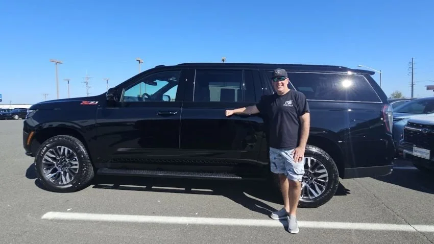 standing in front of 2026 black Chevy Suburban
