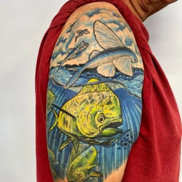 Colorful arm tattoo of mahi mahi chasing flying fish