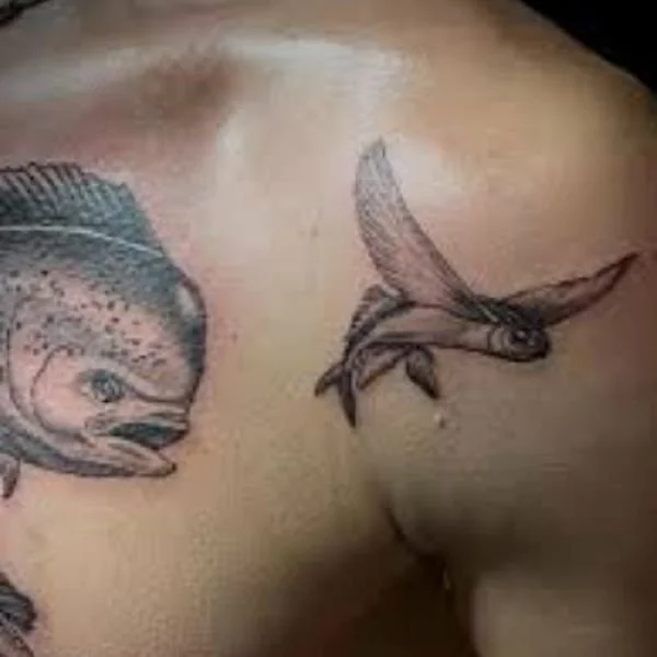 Black and white tattoo of dorado fish chasing a single flying fish