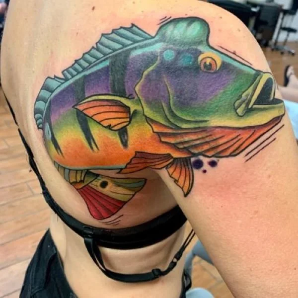 Tattoo of a peacock bass with a hump on its head on a woman's back
