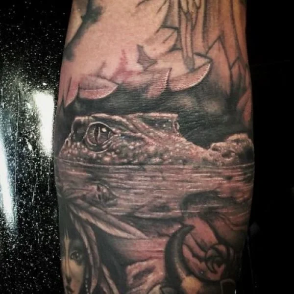 tattoo of caiman head just above surface of Amazon River