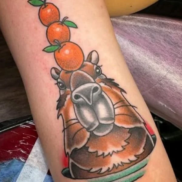 color tattoo of capybara with multiple fruits on its head