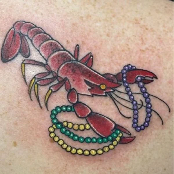 Red crawfish tattoo with Mardi Gras beds in its claws