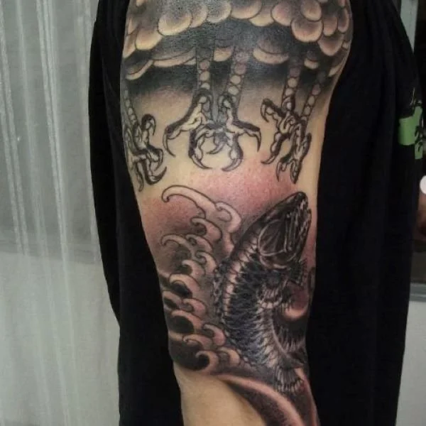 Tattoo of trairao fish getting grabbed by bird talons