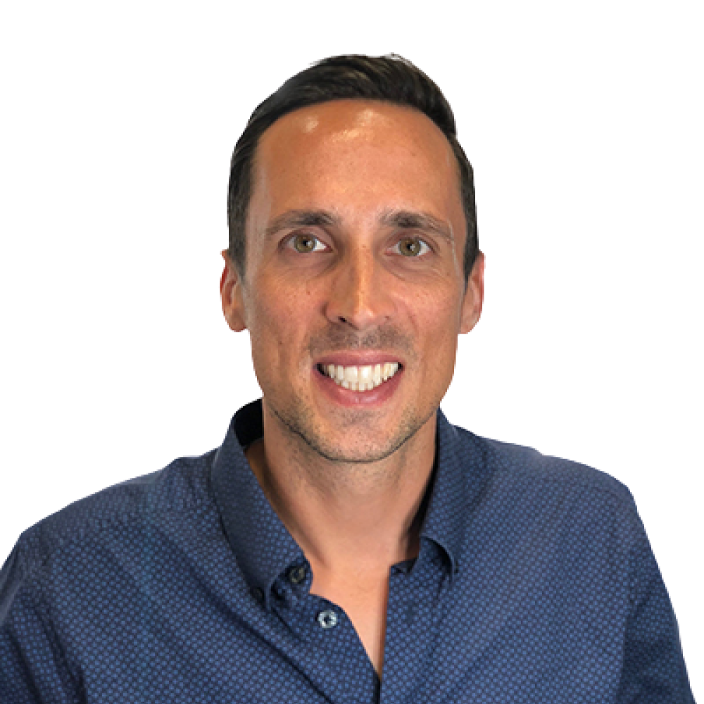 Close-up of a smiling man with short dark hair, wearing a blue button-up shirt, against a plain white background.