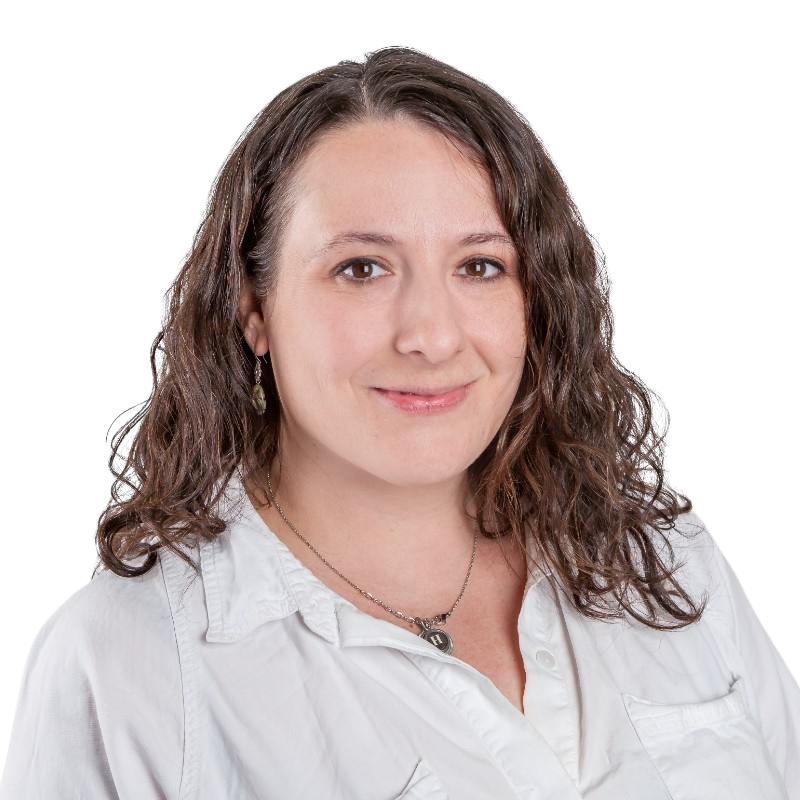 Portrait of a woman with shoulder-length curly brown hair, wearing a white collared shirt and a silver necklace, smiling at the camera.