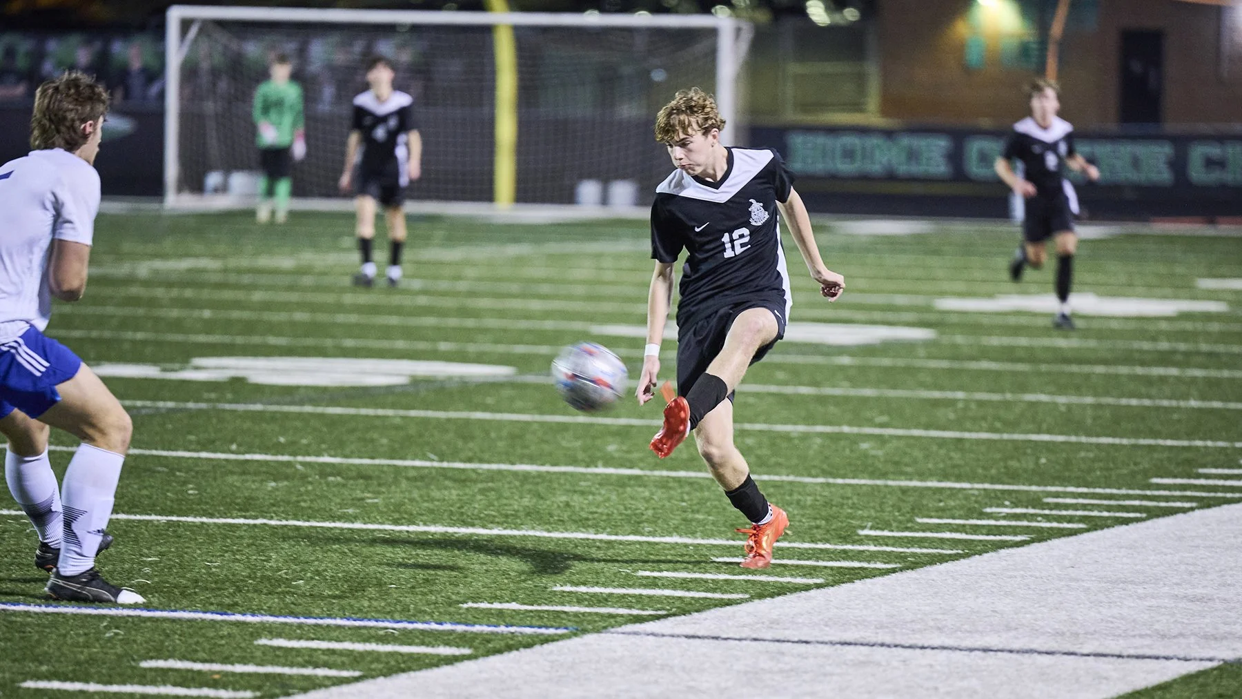Peachtree City High School Soccer Action Photography | South Atlanta Photography
McIntosh High School soccer player in a black-and-white uniform strikes the ball during live game action on a stadium field in Peachtree City, Georgia.