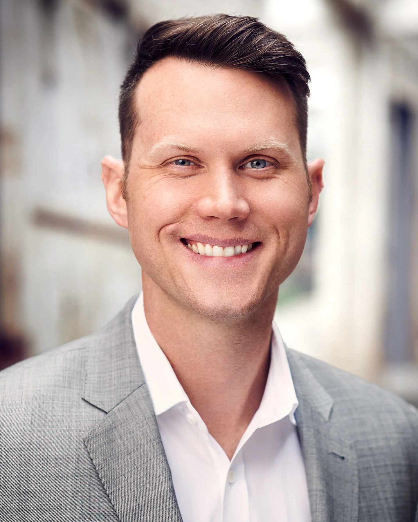 Professional headshot of a smiling male business executive in a light gray suit, photographed outdoors by South Atlanta Photography in Peachtree City, Georgia.