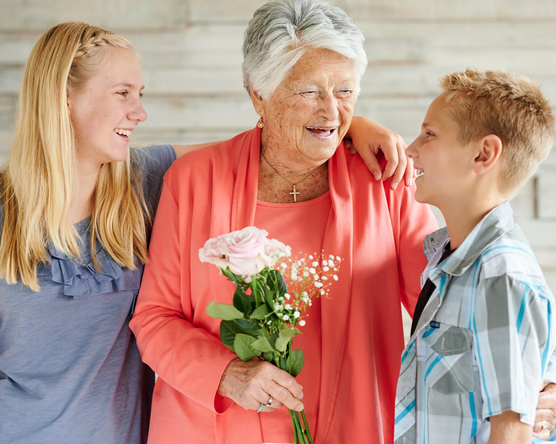 Grandmother smiling with two younger family members during a relaxed multi-generational family portrait session photographed indoors.