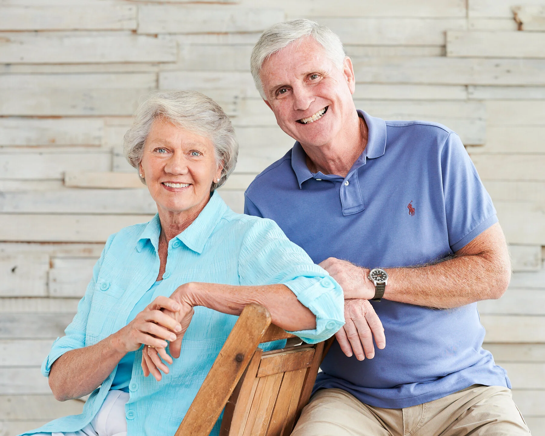 Older married couple smiling together in a relaxed seated portrait during an indoor multi-generational family photography session.