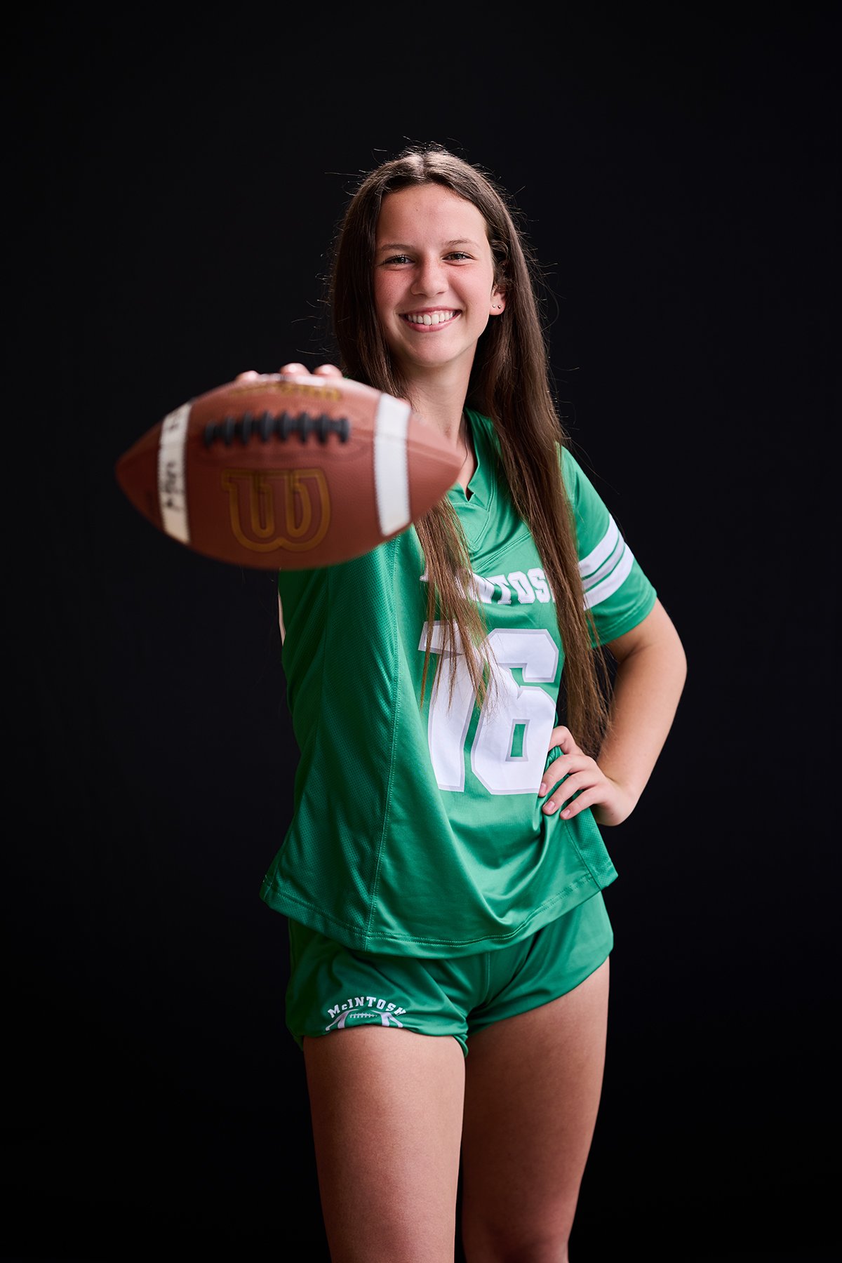 Peachtree City Female Athlete Sports Portrait | South Atlanta Photography
Female McIntosh high school athlete in a green uniform poses against a black background while holding a football during a sports portrait session in Peachtree City, Georgia.