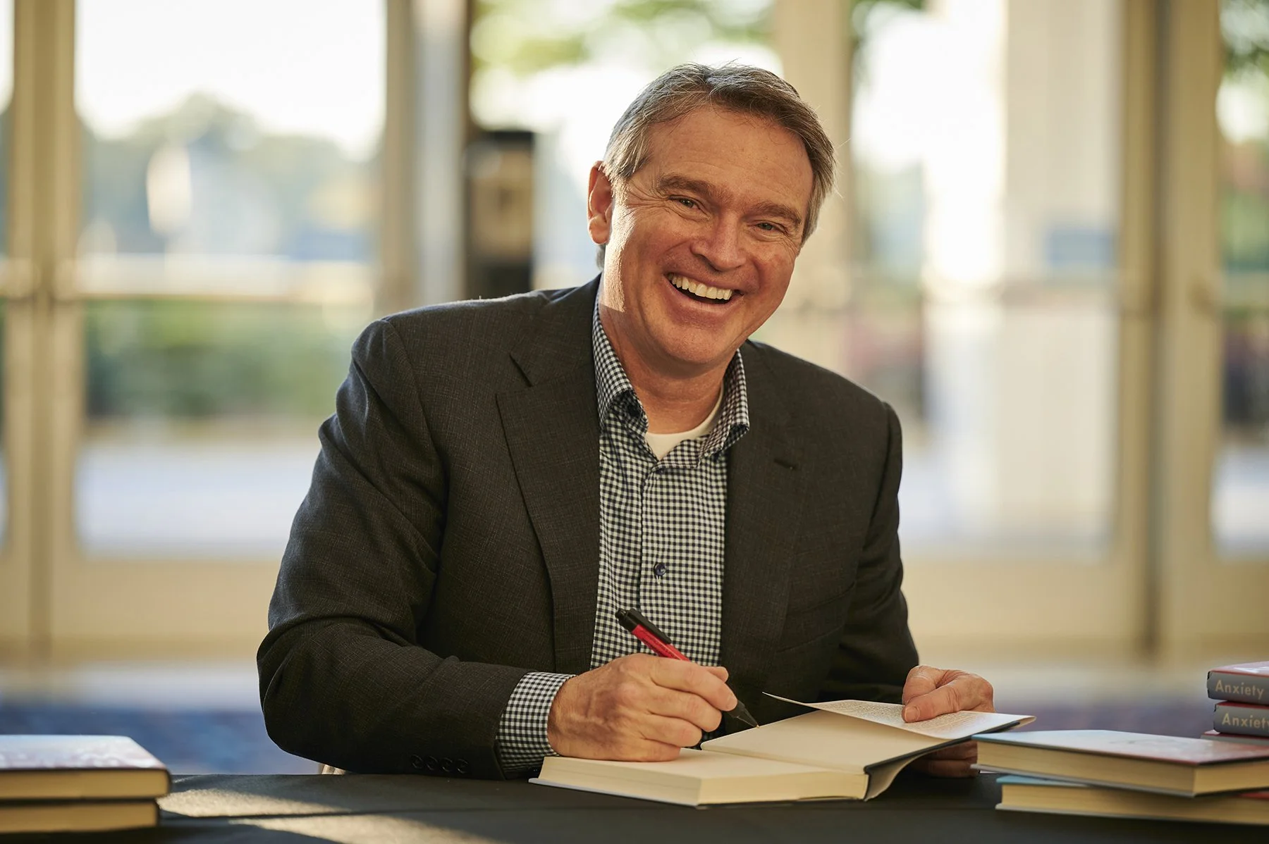 Atlanta Author Appearance and Book Signing Event Photography
Smiling author signs books for guests during a professionally photographed corporate or literary event in Atlanta.