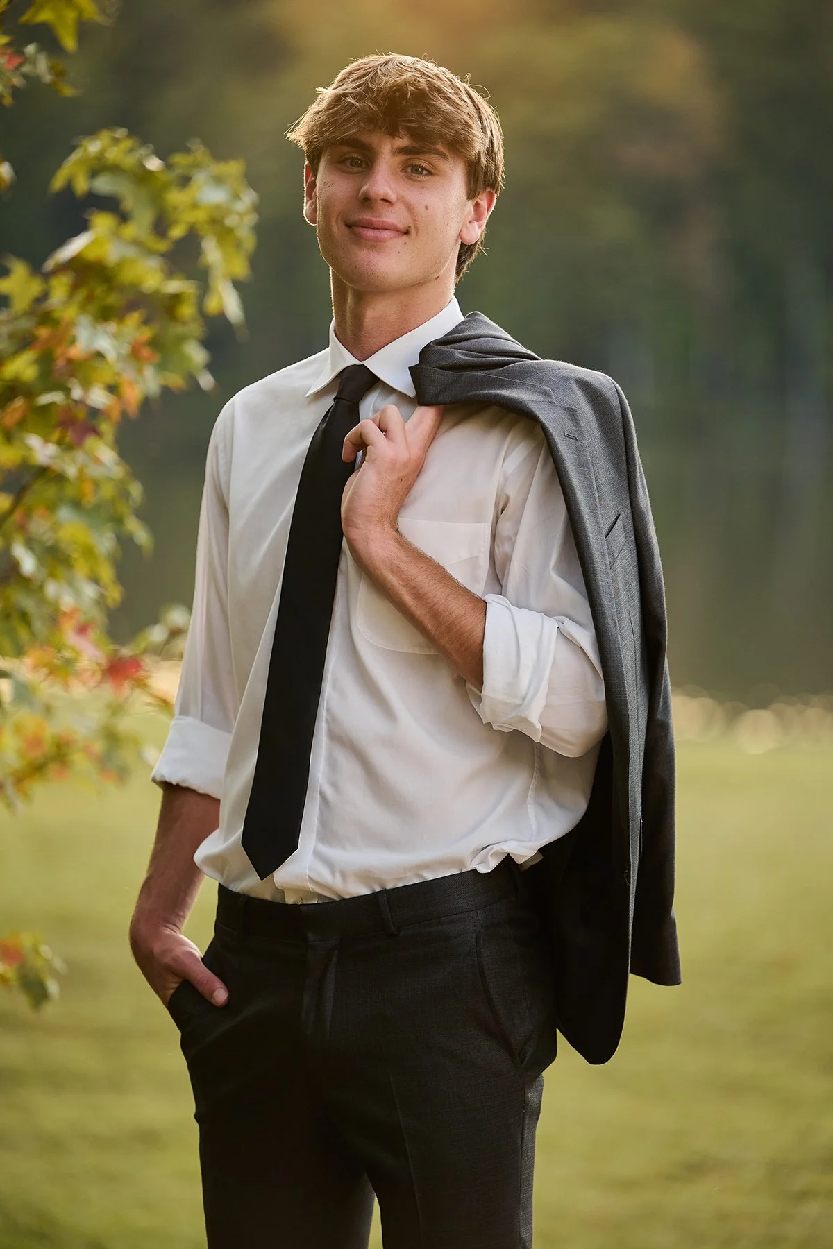 Class of 2027 senior portrait of a guy in dress shirt and tie holding a jacket outdoors, part of a boys senior session in Peachtree City, Georgia.