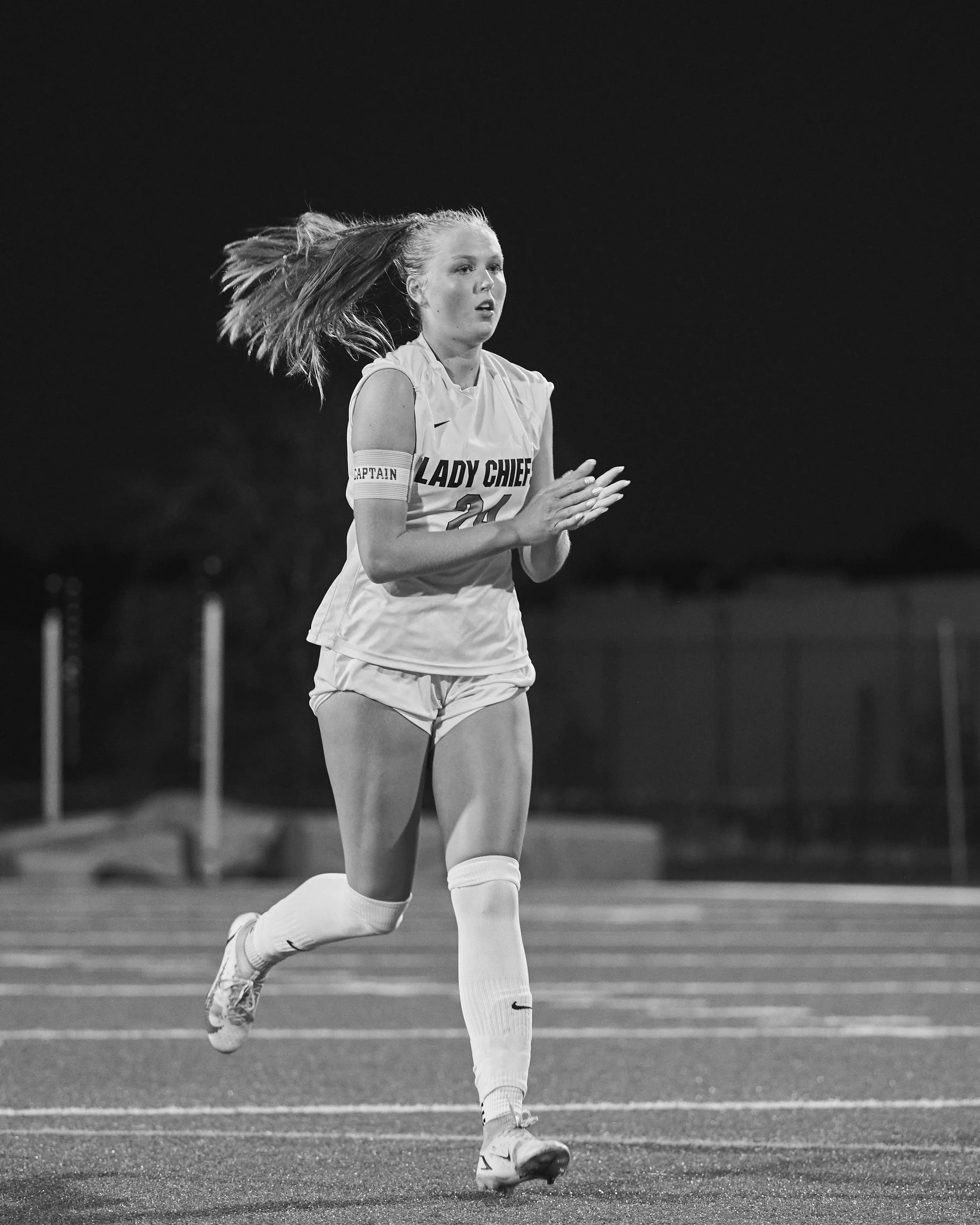 Black-and-white photograph of a female high school soccer player running on the field during live game action in Peachtree City, Georgia.